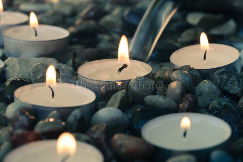 Tea-light candles on pebbles stones selective focus