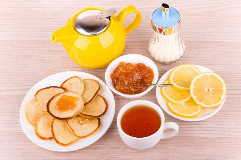 Tea with pancakes, peach jam and lemon, sugar and teapot stock images Tea with pancakes, peach jam and lemon, sugar and teapot stock images