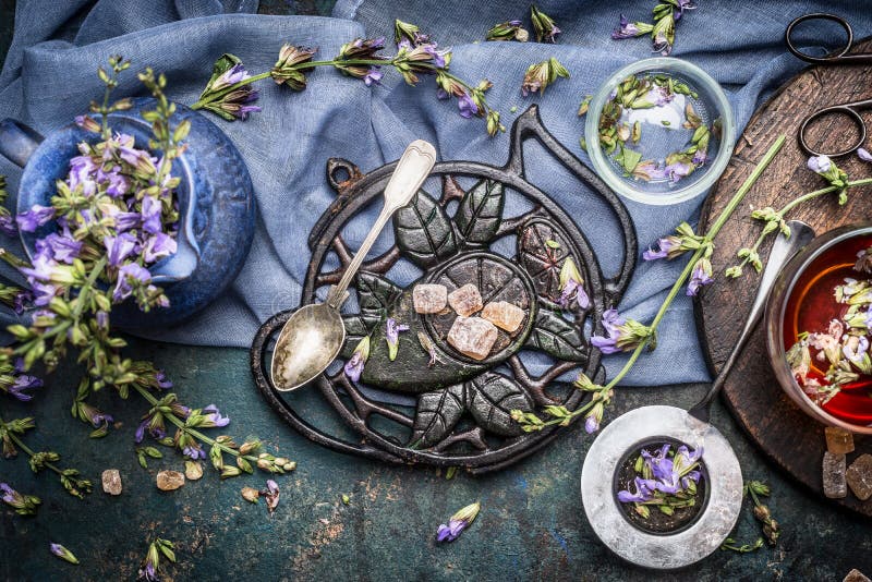Tea time. Herbal tea preparation with fresh flowers ,wild herbs and vintage tea tools on dark rustic background.