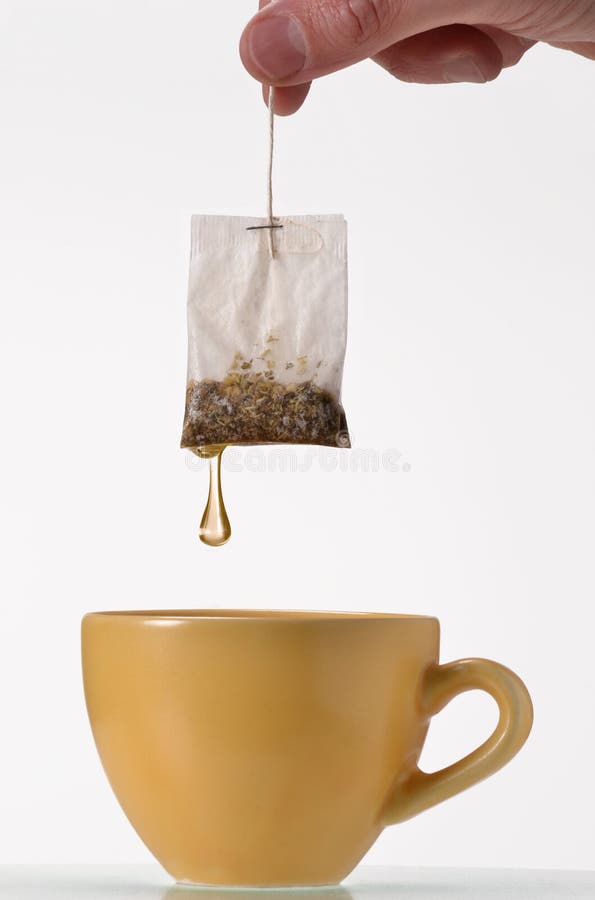 Soaking a tea bag on a yellow cup,Tea bag on cup.Holding tea bag. Soaking a tea bag on a yellow cup,Tea bag on cup.Holding tea bag.
