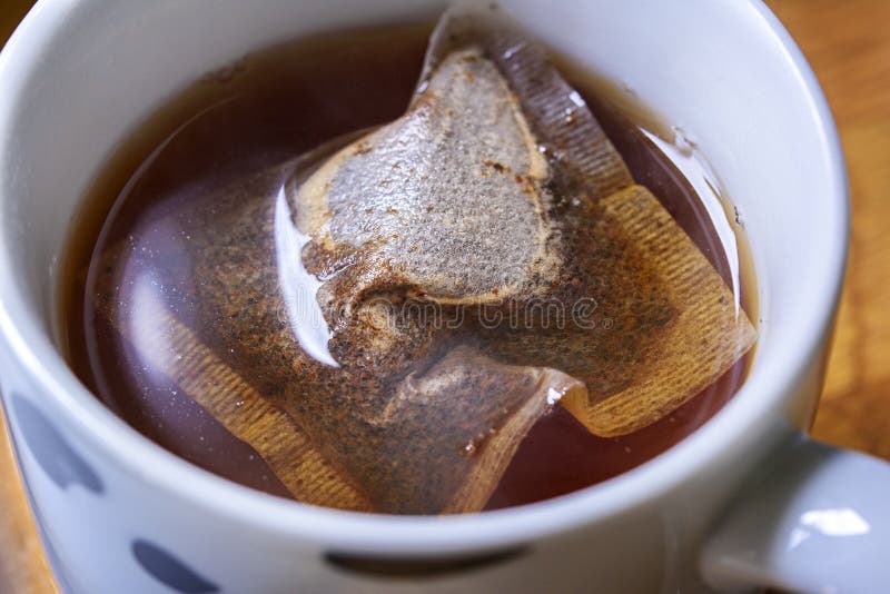 Close up of an earl grey tea bag which is inside a mug of boiling hot water. It is infusing the water and brewing before milk is added to it. Close up of an earl grey tea bag which is inside a mug of boiling hot water. It is infusing the water and brewing before milk is added to it.