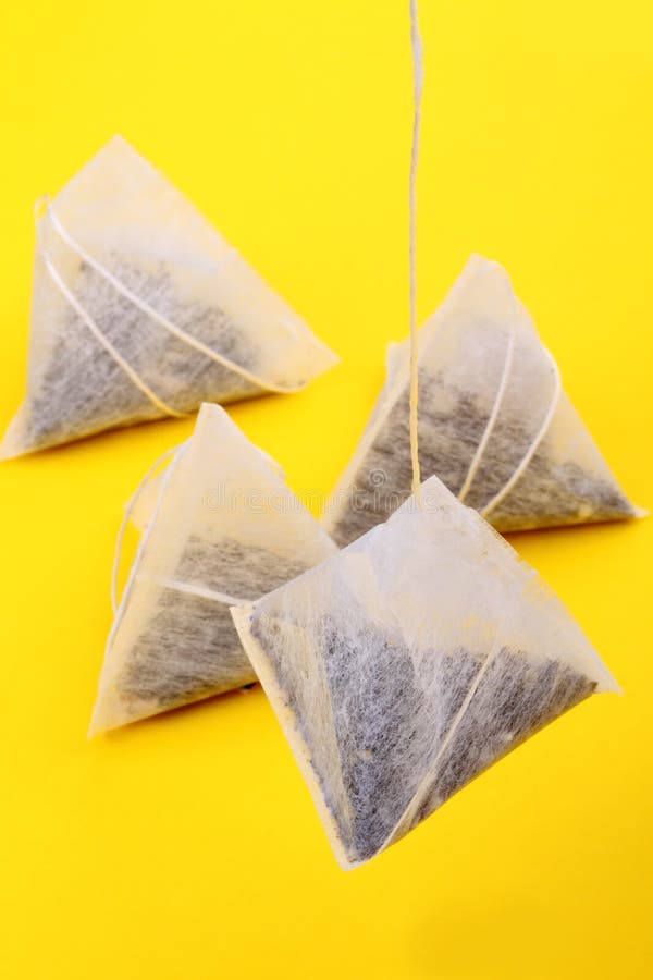 Four tea bags pyramid shape on a yellow background. Four tea bags pyramid shape on a yellow background