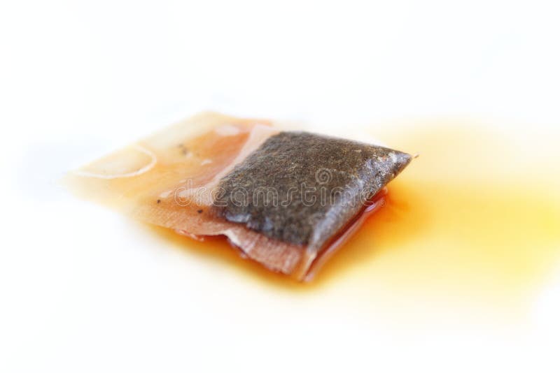 Tea bag steeping in a splash of black tea isolated on white background. Diffusion of substances in liquids. Tea bag steeping in a splash of black tea isolated on white background. Diffusion of substances in liquids.