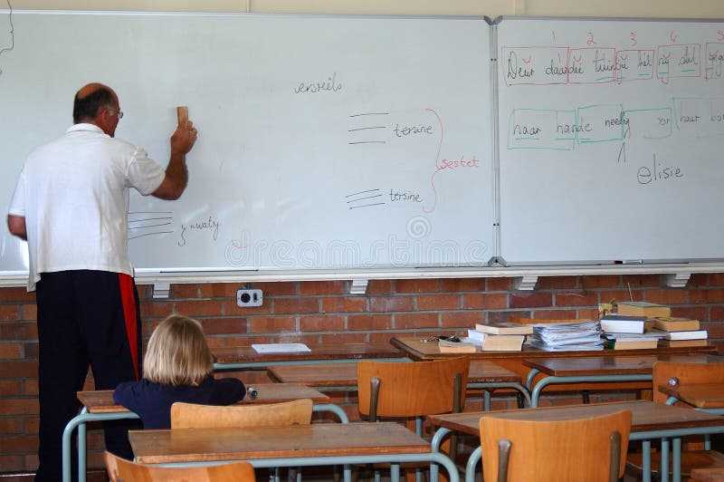Starší kaukazských biela dospelý samec učiteľa pri práci a mladých málo schoolkid v takmer prázdnej triede školy.