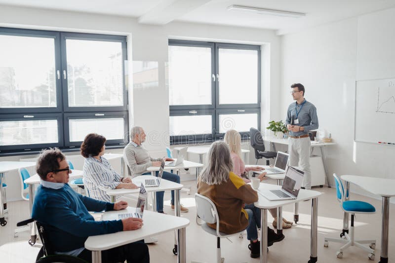 Teacher explaining senior students how to work with laptop and internet. Elderly people attending computer and royalty free stock photography