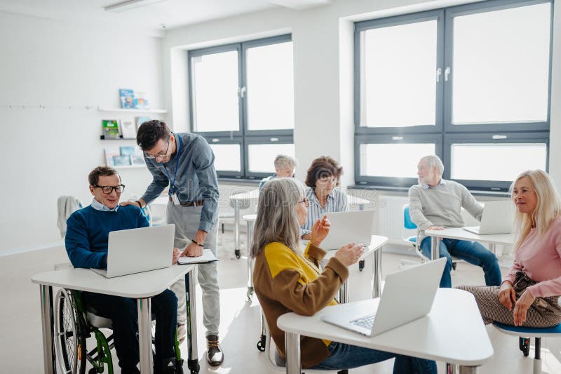 Teacher explaining senior students how to work with laptop and internet. Elderly people attending computer and royalty free stock photo