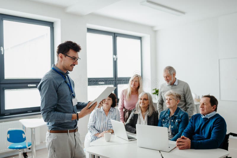 Teacher explaining senior students how to work with laptop and internet. Elderly people attending computer and stock images