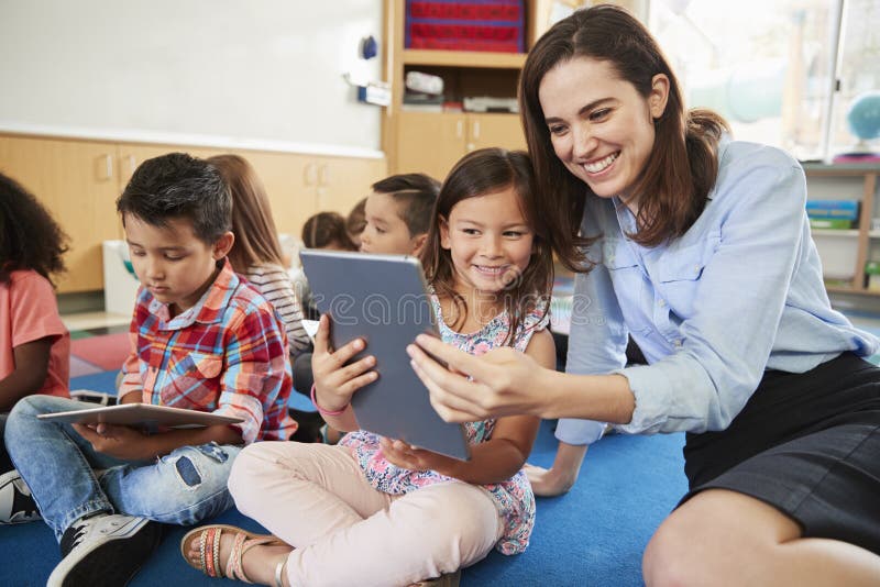 Teacher and girl in elementary class using tablet computers