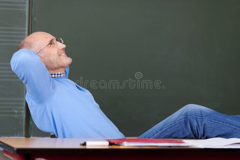 Teacher With Hands Behind Head Looking Up At Desk royalty free stock image
