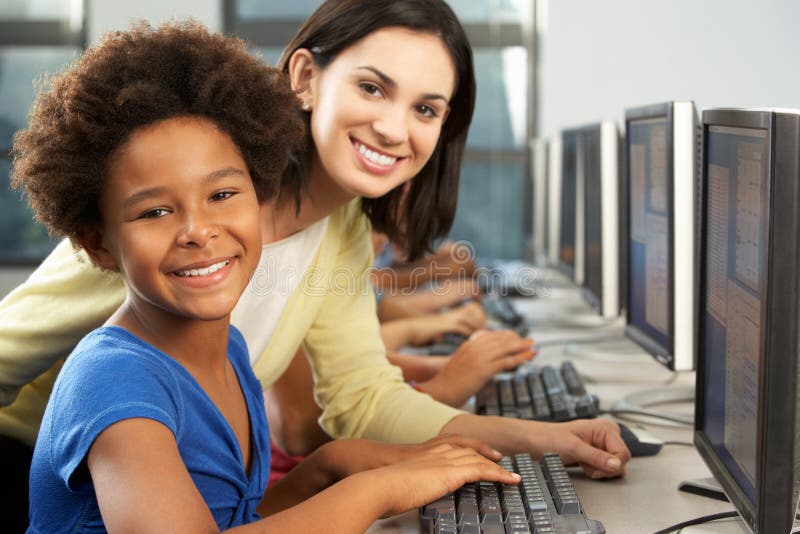 Teacher Helping Elelmentary Students Working At Computers royalty free stock photo