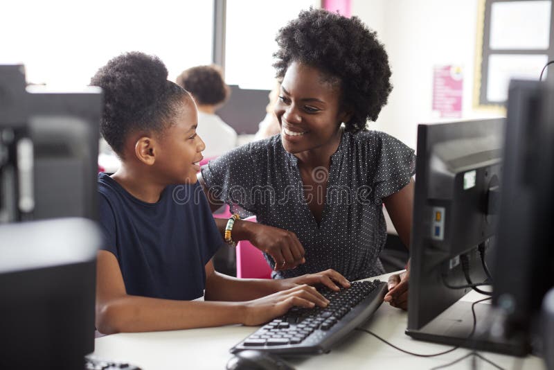 Teacher Helping Female High School Student Working at Screen In Computer Class