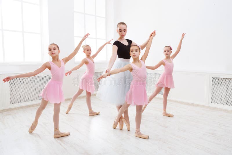 Young ballet teacher and students ballerinas in dance class. Girls are engaged in choreography in the ballet school. Young ballet teacher and students ballerinas in dance class. Girls are engaged in choreography in the ballet school.