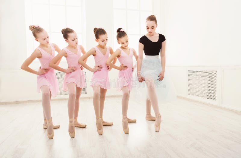 Young ballet teacher and students ballerinas in dance class. Girls are engaged in choreography in the ballet school, copy space. Young ballet teacher and students ballerinas in dance class. Girls are engaged in choreography in the ballet school, copy space