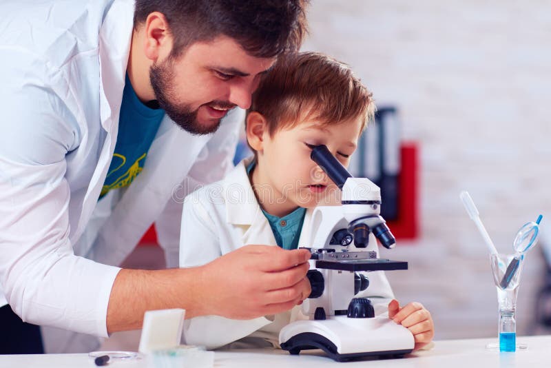 Teacher helps kid to conduct experiment with microscope