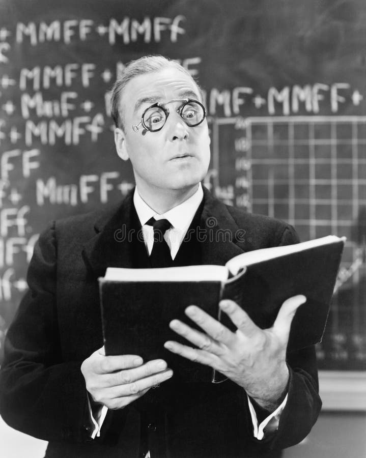 Teacher holding a book in front of a black board looking surprised stock images