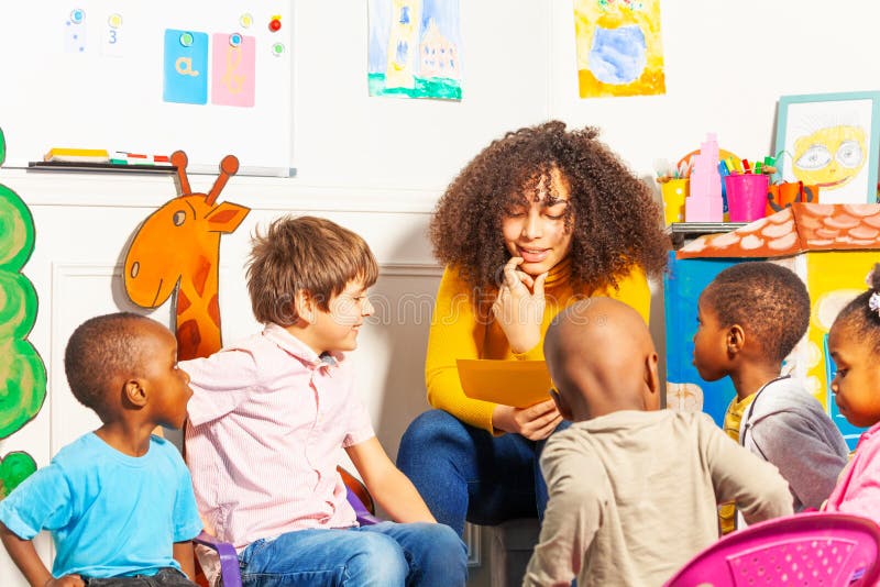 Teacher in kindergarten reading a book to kids royalty free stock photos Teacher in kindergarten reading a book to kids royalty free stock photos