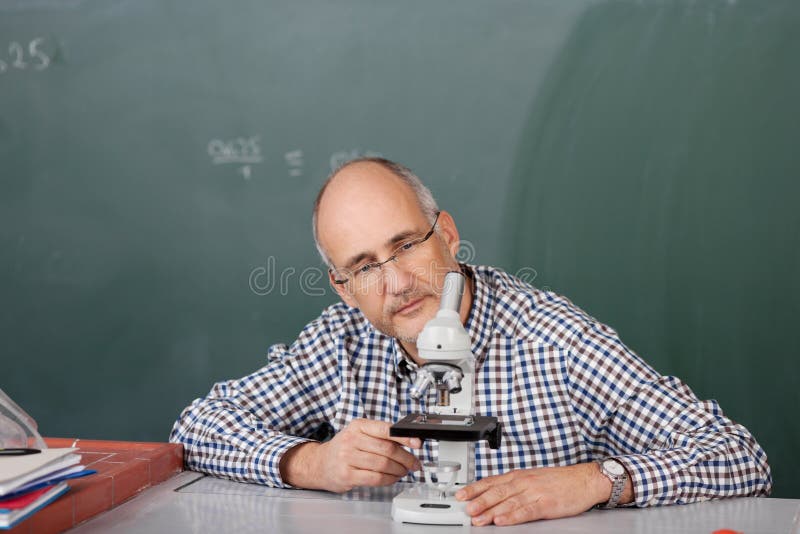 Teacher looking at a microscope stock photo