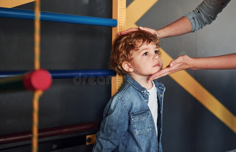Teacher Measuring Kid`s Height Indoors in Kindergarten Stock Image