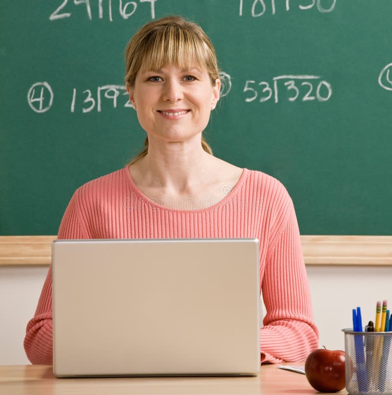 Teacher posing with laptop in school classroom