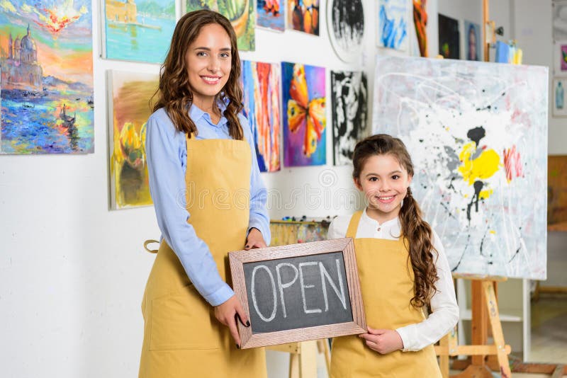 teacher and pupil holding signboard with word open in workshop of stock photos teacher and pupil holding signboard with word open in workshop of stock photos