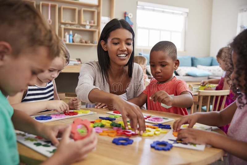 Teacher And Pupils Using Flower Shapes In Montessori School royalty free stock photography