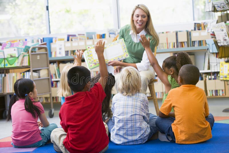 Kindergärtnerin Kindern vorlesen in der Bibliothek.