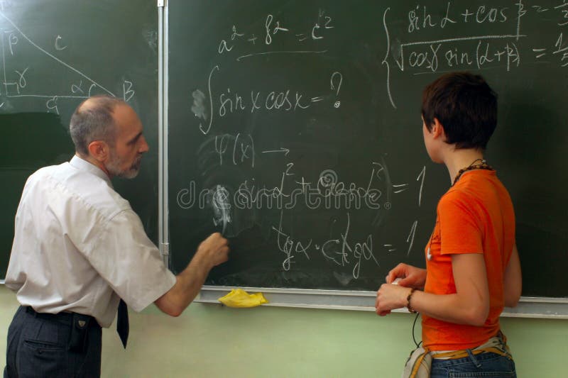 The teacher and the schoolgirl near blackboard. Lesson of mathematics. The teacher and the schoolgirl near blackboard. Lesson of mathematics