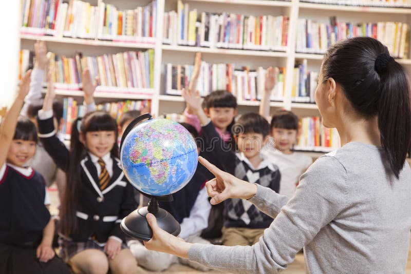 Teacher teaching geography to schoolchildren with a globe stock images Teacher teaching geography to schoolchildren with a globe stock images