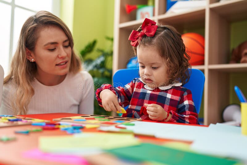 Teacher and Toddler Playing with Maths Puzzle Game Sitting on Table at