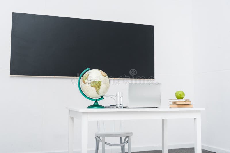 Teachers desk in classroom in front of chalkboard