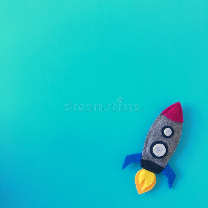 Blue background with small rocket toy hand made from felt fabric. Colorful handmade toy flat lay. Colorful crafting supplies space ship top view photography from above with copy space, text area, spaceship, universe, galaxy, cosmos, missile, texture, bright, happy, colors, template, banner, square, header, diy, project, crafts, art, boys, children, theme, announcement, card, creation, creative, inspiration, idea, isolated, baby, crib, mobile, nursery, ornament, modern, teal. Blue background with small rocket toy hand made from felt fabric. Colorful handmade toy flat lay. Colorful crafting supplies space ship top view photography from above with copy space, text area, spaceship, universe, galaxy, cosmos, missile, texture, bright, happy, colors, template, banner, square, header, diy, project, crafts, art, boys, children, theme, announcement, card, creation, creative, inspiration, idea, isolated, baby, crib, mobile, nursery, ornament, modern, teal