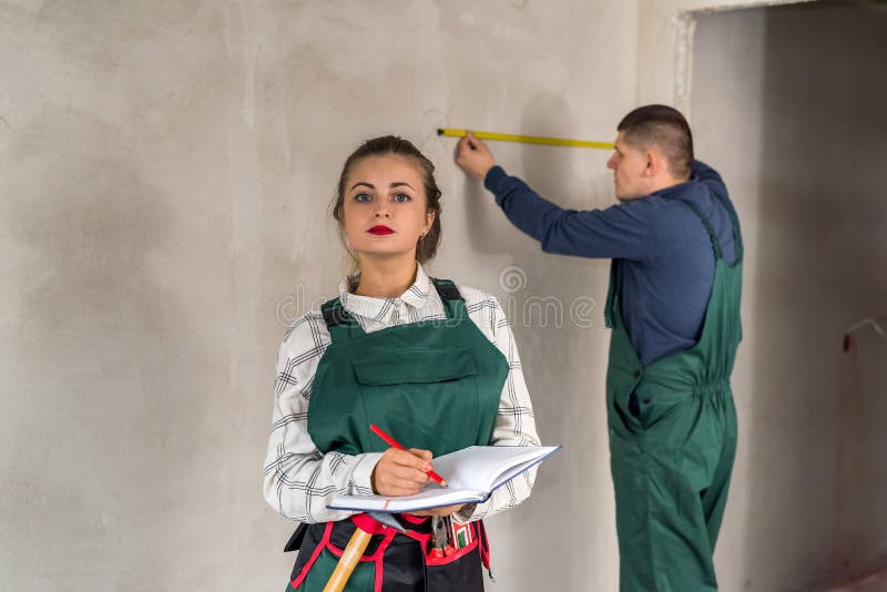 Team of builders measuring walls and writing in notepad stock images Team of builders measuring walls and writing in notepad stock images