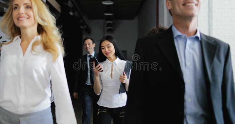 Team of business people walking in office while asian businesswoman answer phone call