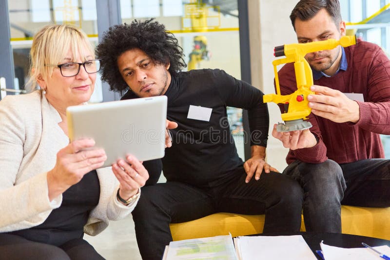 Team collaborating on robotics development with tablet and robot model in office setting royalty free stock images