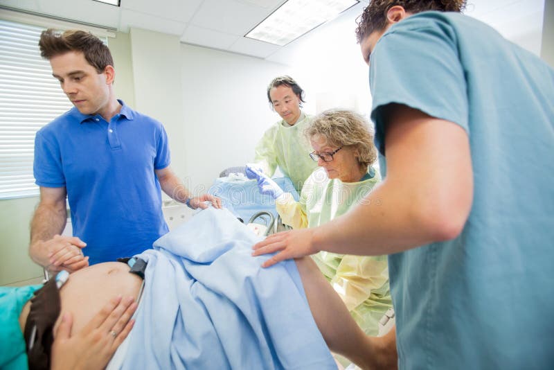 Team Examining Pregnant Woman During médico imagen de archivo libre de regalías Team Examining Pregnant Woman During médico imagen de archivo libre de regalías