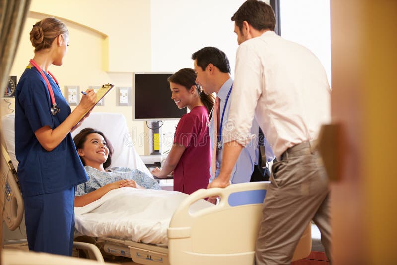Team Meeting Around Female Patient medico nella stanza di ospedale fotografie stock Team Meeting Around Female Patient medico nella stanza di ospedale fotografie stock