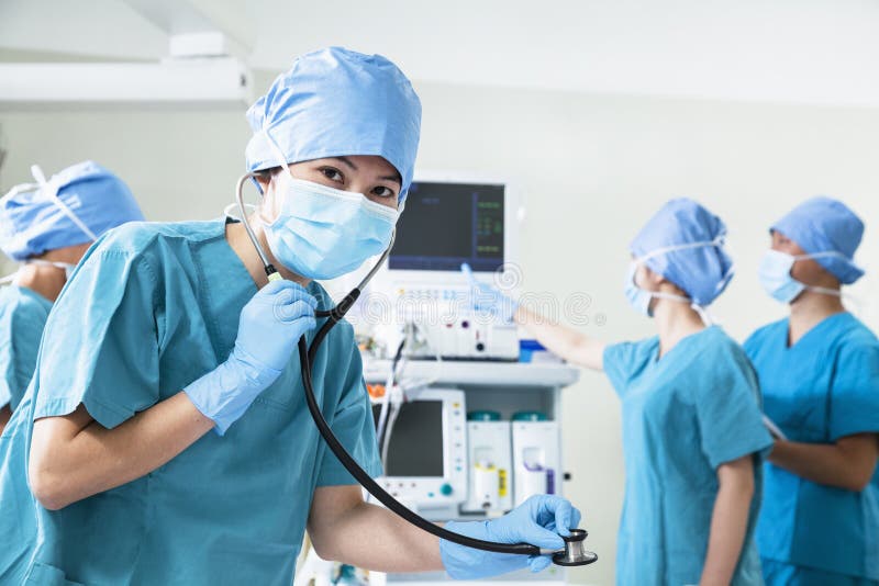Team of surgeons in the operating room, female surgeon holding stethoscope and looking at camera royalty free stock images