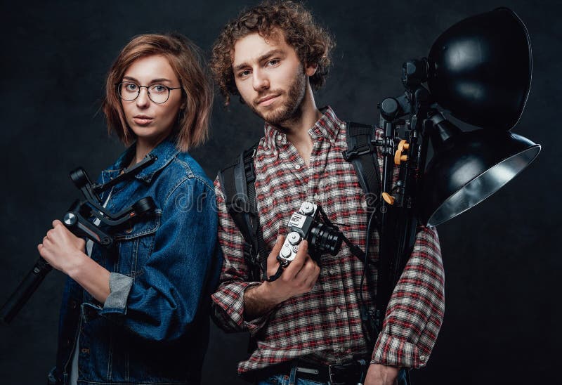 The Team of Two Young Photographers Holds a Digital Camera and Lighting