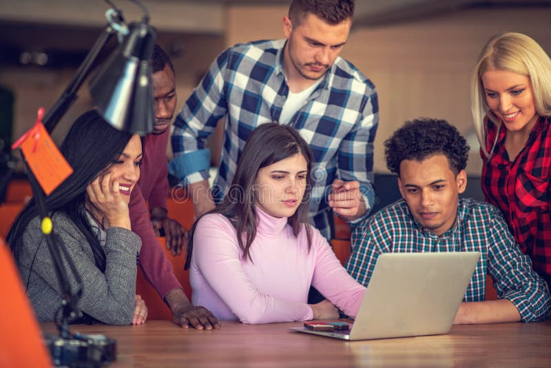 Team van creatieve mensen die kijken naar collega die het projectplan op zijn laptop toont royalty-vrije stock afbeelding Team van creatieve mensen die kijken naar collega die het projectplan op zijn laptop toont royalty-vrije stock afbeelding