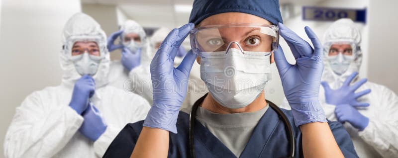Team van vrouwelijke en mannelijke artsen of verpleegkundigen die in de ziekenhuisgang persoonlijke beschermingsmiddelen dragen