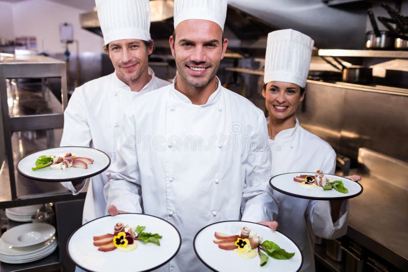 Team von den Chefs, die ihre Teller darstellen lizenzfreies stockbild Team von den Chefs, die ihre Teller darstellen lizenzfreies stockbild