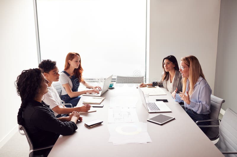 Team Of Young Businesswomen In Meeting Around Table In Modern Workspace stock photography