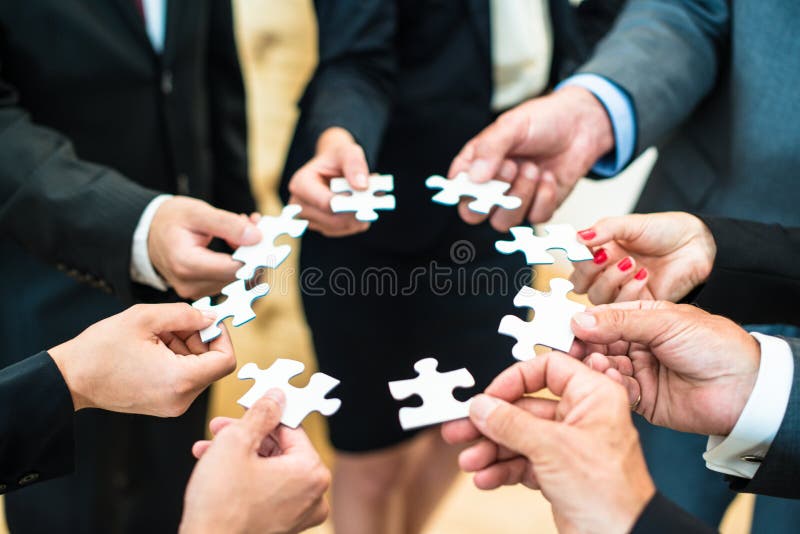 Teamwork - Business people solving a puzzle. Teamwork - a group of eight business people assembling a jigsaw puzzle - representing team support and help concepts stock photography Teamwork - Business people solving a puzzle. Teamwork - a group of eight business people assembling a jigsaw puzzle - representing team support and help concepts stock photography
