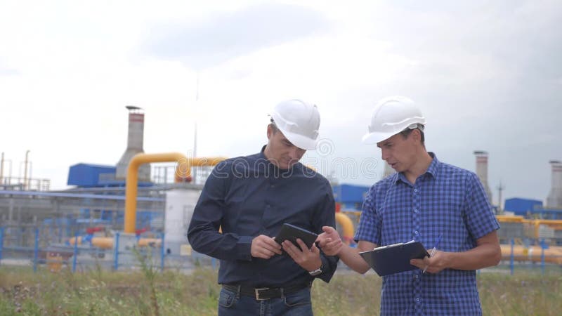 teamwork conceito da estação da produção do gás da indústria v?deo de movimento lento dois coordenadores nos capacetes estão estu