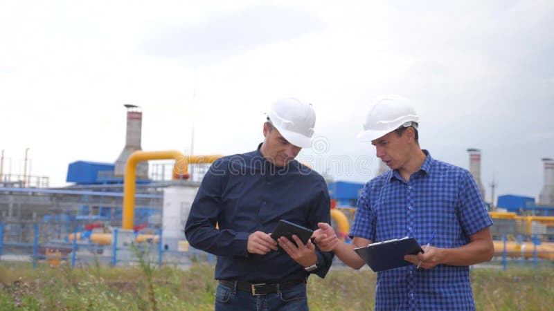 teamwork conceito da estação da produção do gás da indústria v?deo de movimento lento dois coordenadores nos capacetes estão estu