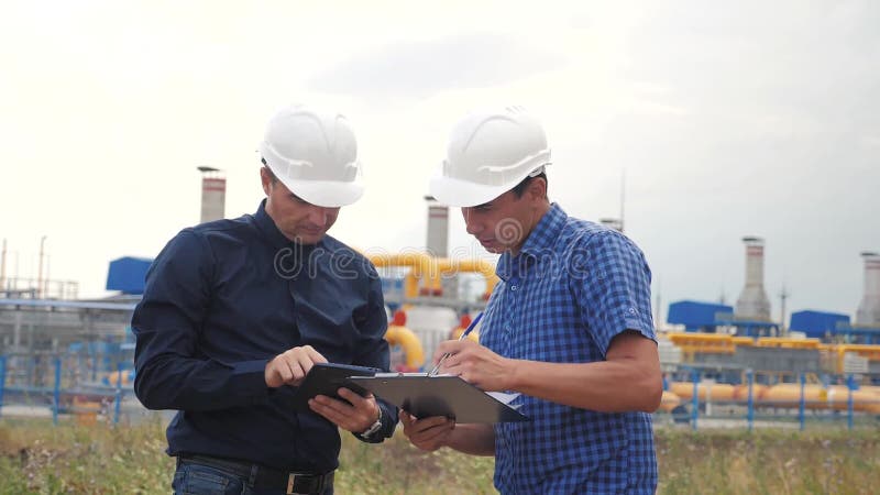 teamwork conceito da estação da produção do gás da indústria v?deo de movimento lento dois coordenadores nos capacetes estão estu