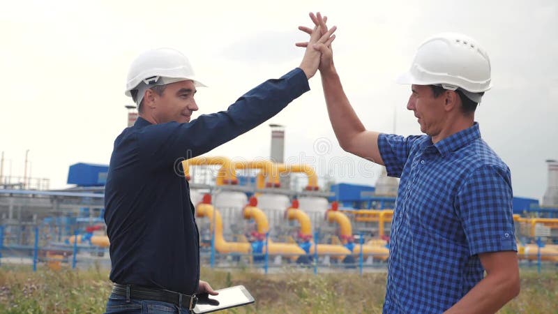 teamwork Conceito da estação da produção do gás da indústria v?deo de movimento lento Dois coordenadores nos capacetes que agitam