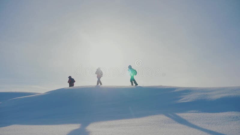 teamwork Manntouristen, die gehendes Spitzengebirgsfelsenhöchstgruppenteam-Sonnenlichtschattenbild auf Schneefuß-Winterschnee kle