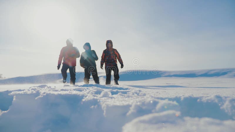 teamwork Manntouristen, die gehendes Spitzengebirgsfelsenhöchstgruppenteam-Sonnenlichtschattenbild auf Schneefuß-Winterschnee kle