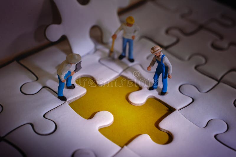 Teamwork and Solving Problem Concept. Group of Miniature Worker Men Found Something Wrong on the Work Process a Piece of Jigsaw stock photo Teamwork and Solving Problem Concept. Group of Miniature Worker Men Found Something Wrong on the Work Process a Piece of Jigsaw stock photo